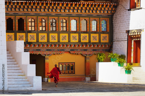 Young monk runs through courtyard in Paro Dzong, a fortress and Buddhist monastery, a sample of the traditional  architecture in the Kingdom of Bhutan.