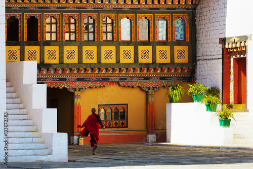 Young monk runs through courtyard in Paro Dzong, a fortress and Buddhist monastery, a sample of the traditional  architecture in the Kingdom of Bhutan. photo