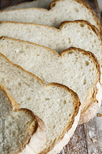 Fresh baked bread and sliced bread on rustic wooden table