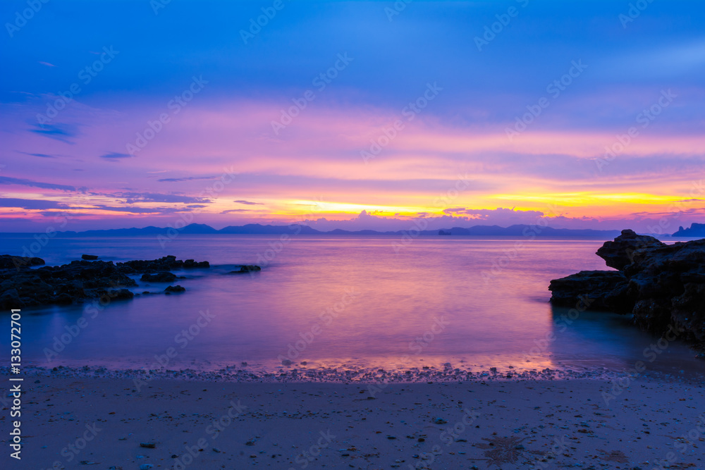 beautiful twilight sunset sky over sea with rocks in foreground