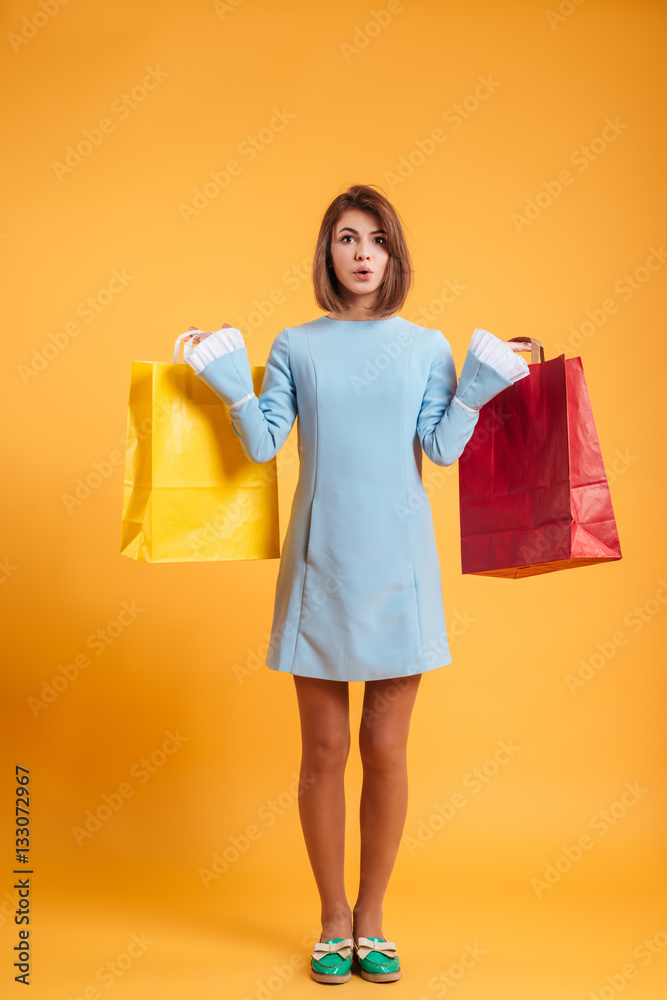 Full length of beautiful young woman holding colorful shopping bags