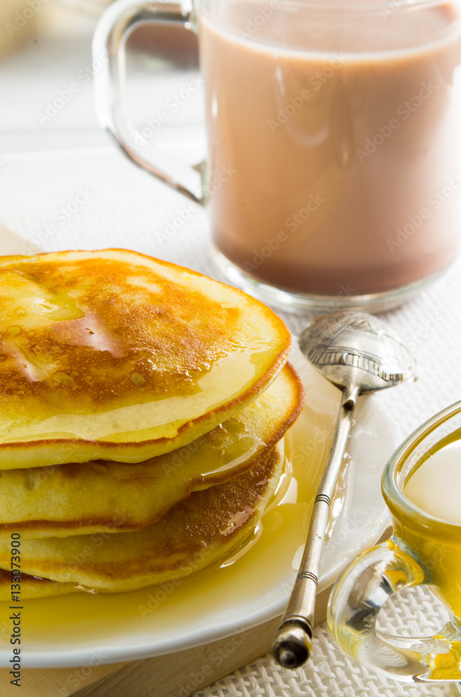 Glass mug with cocoa, silver spoon, honey and pancakes Glass mug with cocoa, silver spoon, honey and pancakes