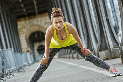 healthy woman stretching on Pont de Bir-Hakeim bridge in Paris