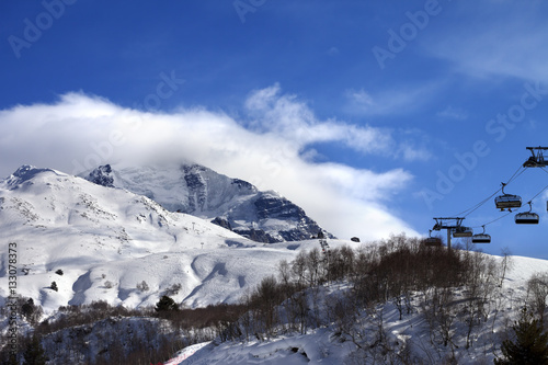 Ski-lift, off-piste slope and mountain in clouds