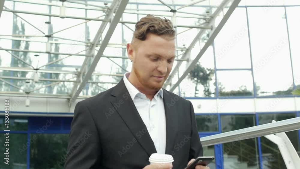 Adult, confident businessman walks along the office buildings Adult, confident businessman walks along the office buildings