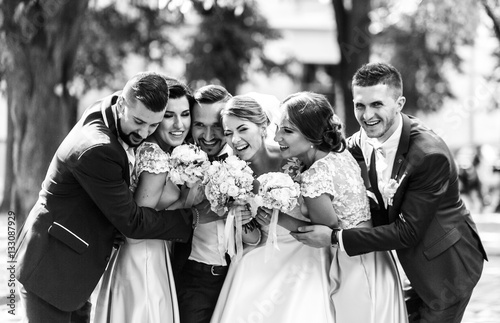 Tighty hugs of newlyweds, groomsmen and bridesmaids standing in photo