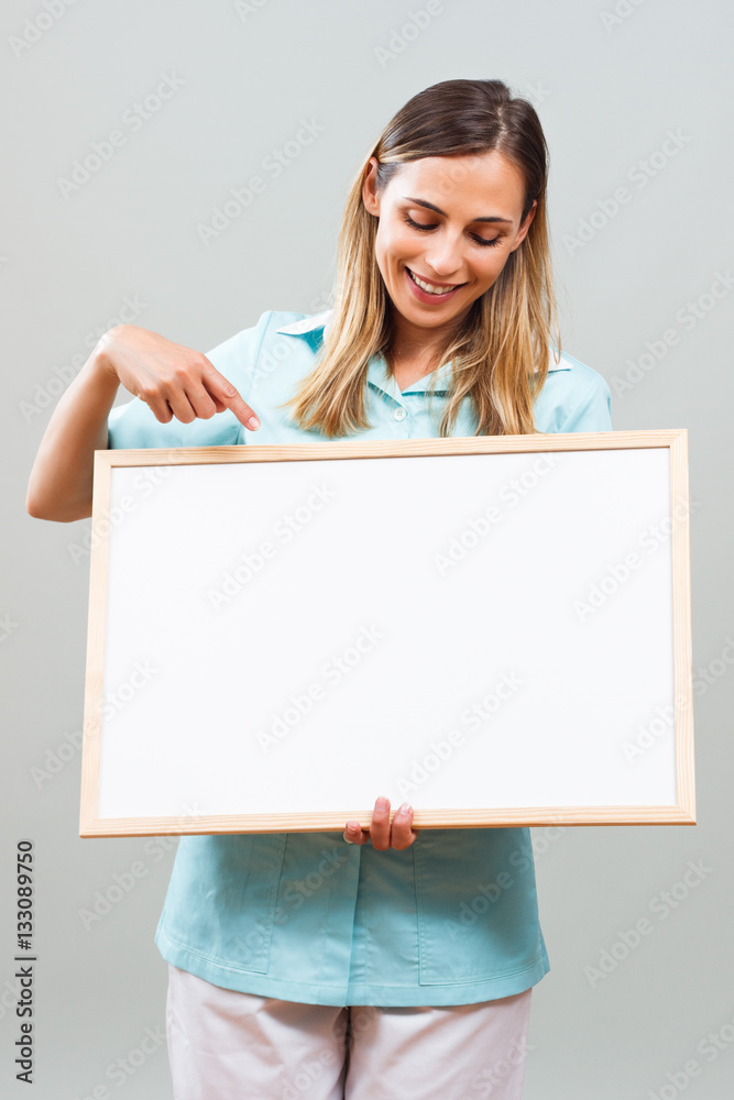 Beautiful nurse is holding whiteboard and pointing.
Beautiful nurse is holding whiteboard and pointing.