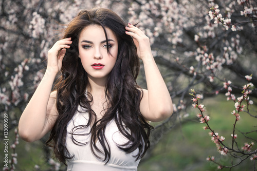 Beautiful girl standing at blossoming tree in the garden