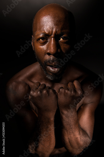 Black man with clenched fists and suffering in emotional pain,