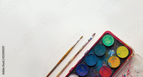 Water color pallet with two paint brushes next to it with a white background photo