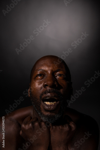Black man with clenched fists and suffering in emotional pain,