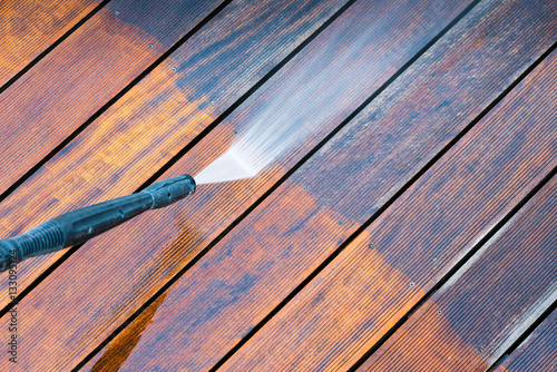 cleaning terrace with a power washer - high water pressure cleaner on wooden terrace surface