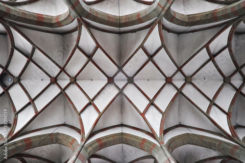 Arched ceiling of gothic church. Stone frame and white filling. Symmetrical form, look up.