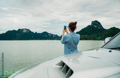woman traveler taking pictures on the smartphone landscape mountain. Stop in the journey for taking photos, and share them on social networks. © galaganov