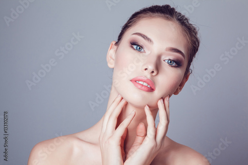 Beautiful brunette girl with makeup on grey background, youth and skin care concept.