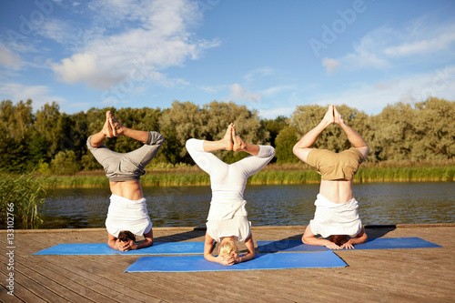 people making yoga headstand on mat outdoors photo