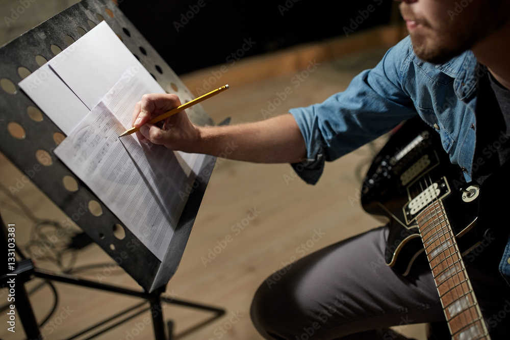 man with guitar writing to music book at studio - obrazy, fototapety, plakaty 