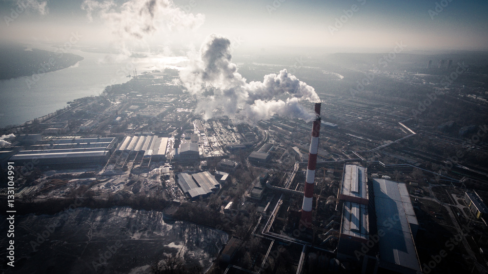 Fototapeta premium Air pollution by smoke coming out of two factory chimneys. Industrial zone in the city. Kiev, Ukraine, aerial view