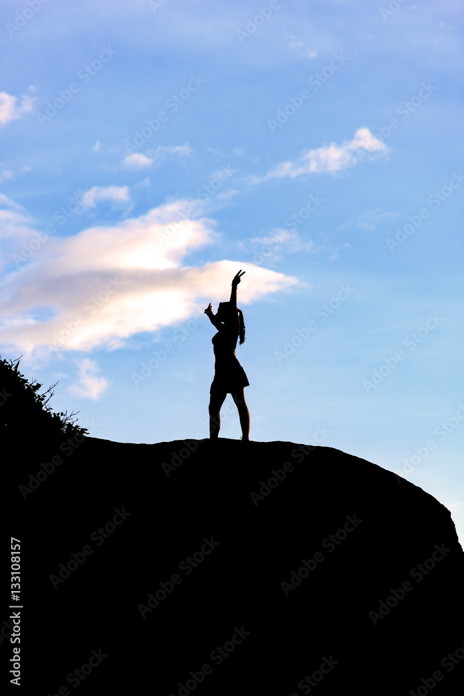 Woman with open arms over stone during sunset Woman with open arms over stone during sunset