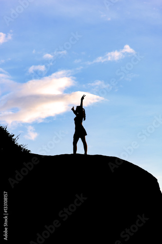 Woman with open arms over stone during sunset