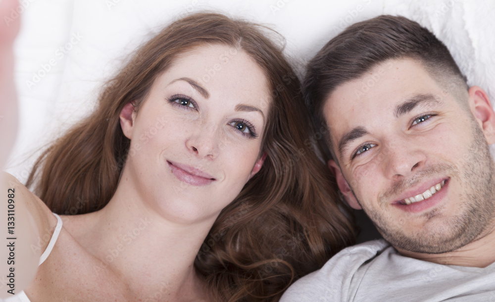paar liegt im bett und macht selfie paar liegt im bett und macht selfie