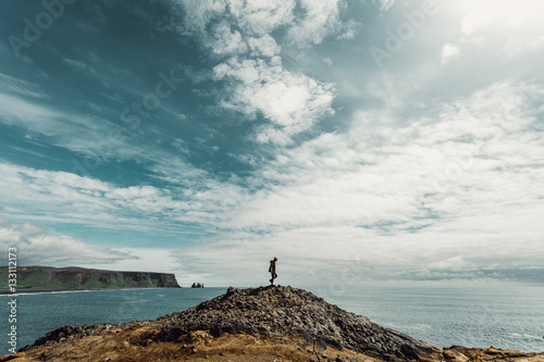 Person stood on rock formation by sea 