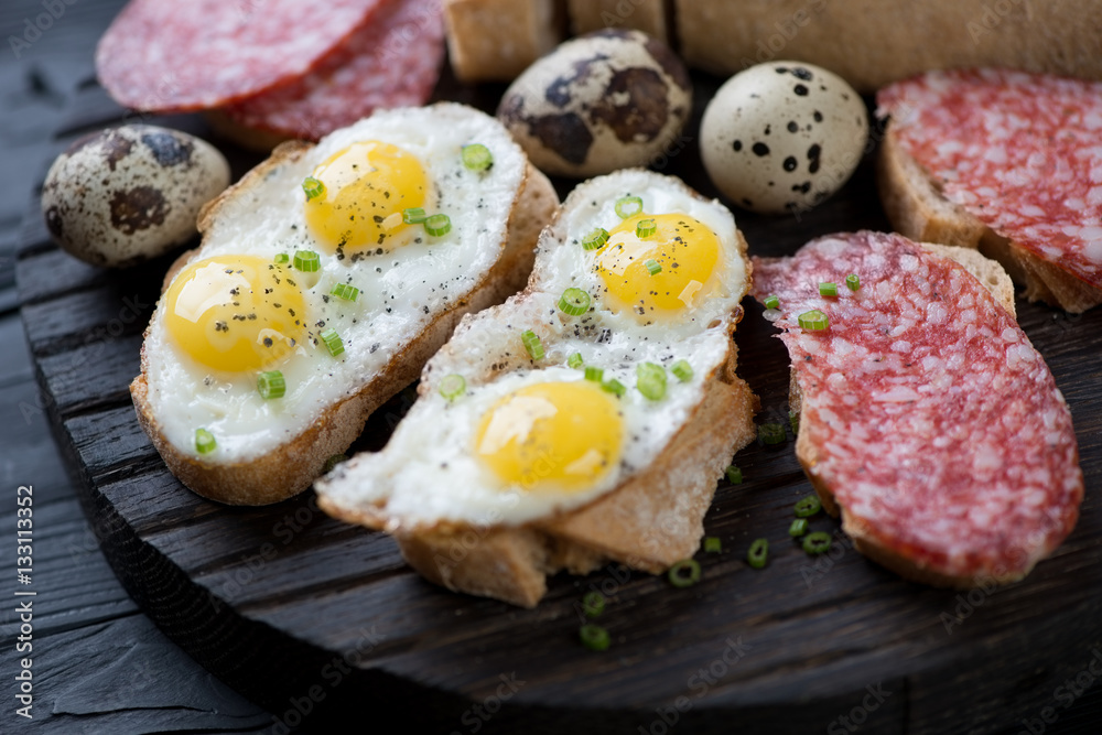 Close-up of bruschettas with fried quail eggs and salami Close-up of bruschettas with fried quail eggs and salami