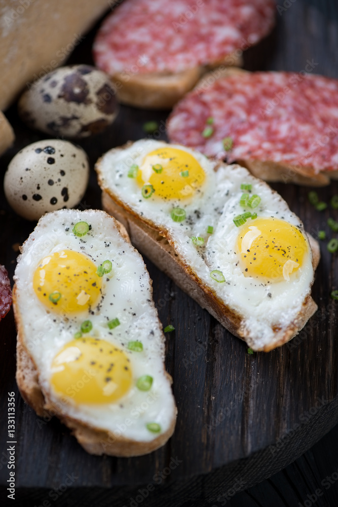 Bruschettas with fried quail eggs, close-up, selective focus Bruschettas with fried quail eggs, close-up, selective focus