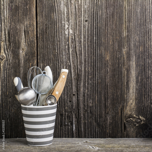 Cookware in gray and tools on a wooden kitchen shelf in the background rustic  wall. The horizontal design