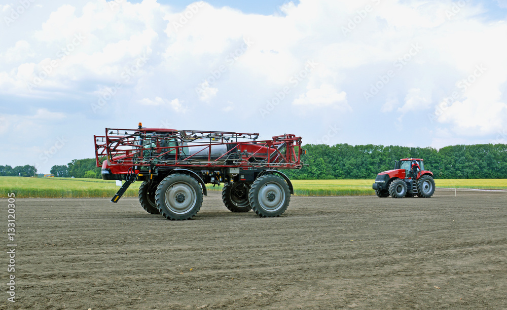 Fototapeta premium Сельскохозяйственный опрыскиватель и трактор на поле
