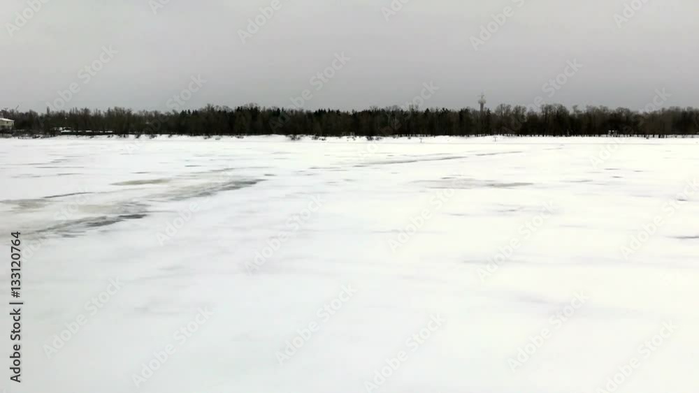KIEV, UKRAINE, JANUARY, 2017. Camera pan from frozen Dnipro river beach bank to Parkovyi Bridge on a cold winter afternoon. Low angle handheld stabilized shot KIEV, UKRAINE, JANUARY, 2017. Camera pan from frozen Dnipro river beach bank to Parkovyi Bridge on a cold winter afternoon. Low angle handheld stabilized shot