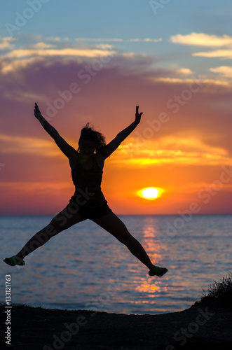 silhouette of jumping girl on a background of sea sunset