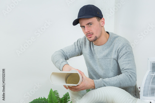 young technician installing air conditioning system indoors photo