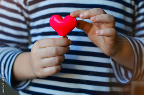 child holding a small pink heart. symbol of love, family, hope. Backgrounds for cards on Valentine's Day. Backgrounds for social posters about the preservation of the family and children.