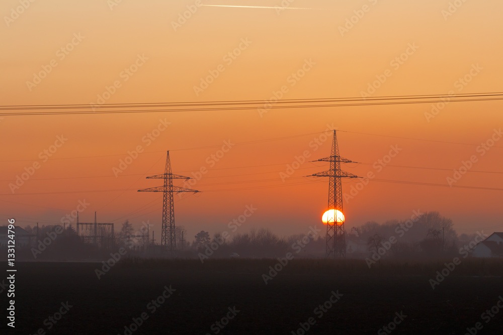 Orange Sunset with Power Poles in Germany in autumn with fog