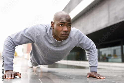 Fitness black man exercising push ups in urban background