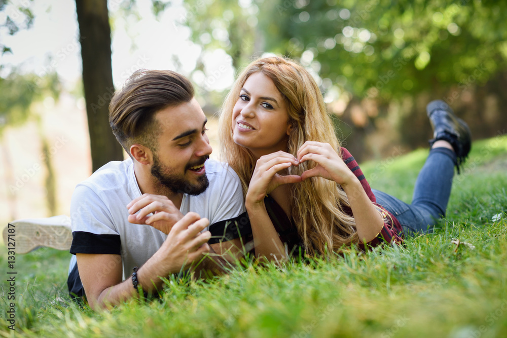 Beautiful young couple laying on grass in an urban park. Beautiful young couple laying on grass in an urban park.