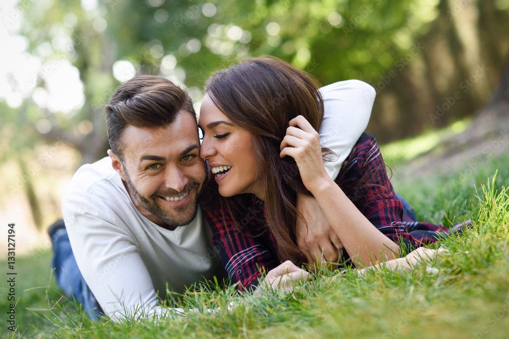 Beautiful young couple laying on grass in an urban park. Beautiful young couple laying on grass in an urban park.