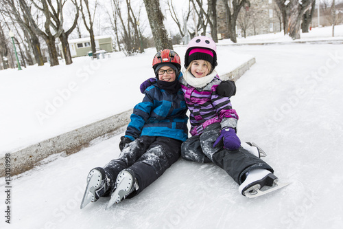 little girl and brother enjoying ice skating in winter season photo