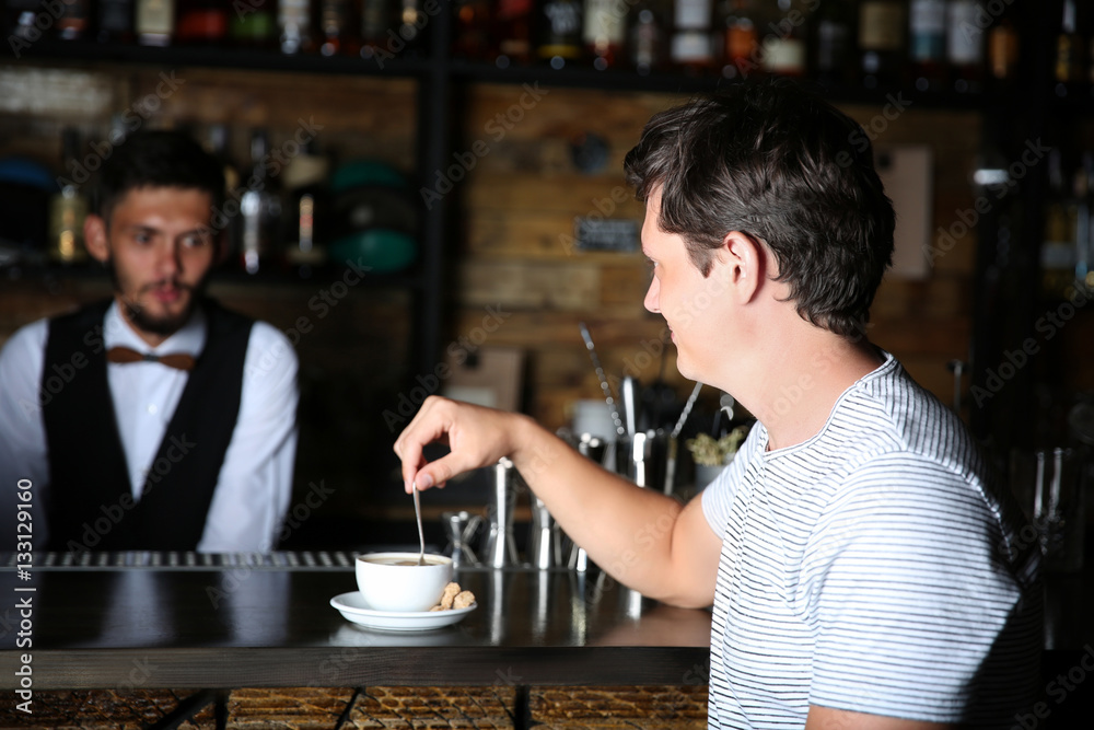 Man with cup of coffee at bar counter