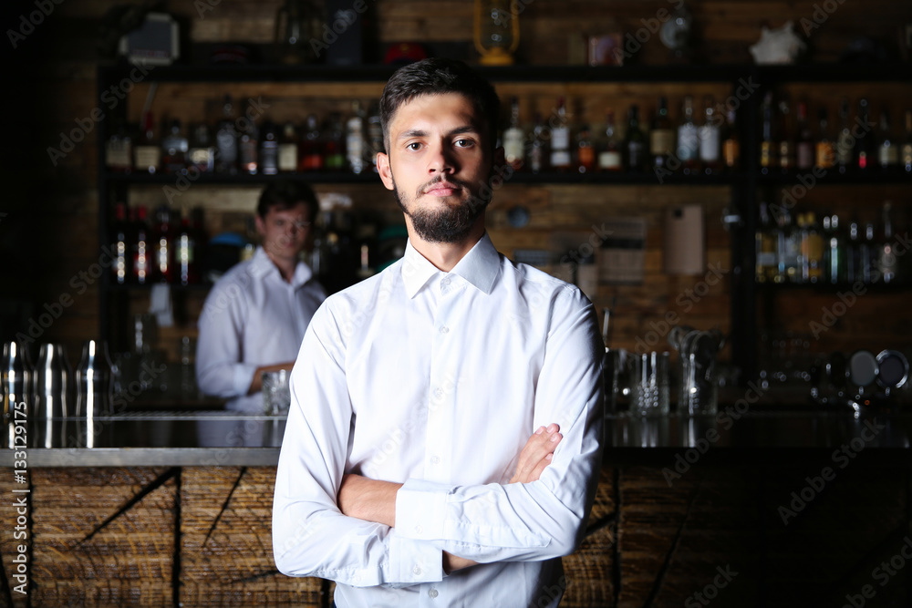 Fototapeta premium Man in white shirt standing at wooden bar counter