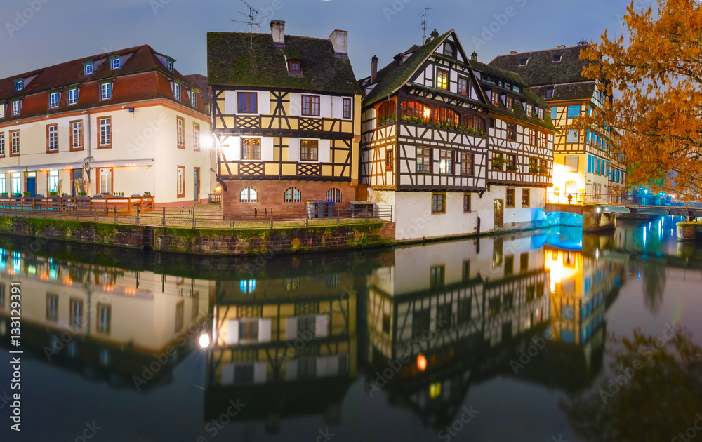 Panorama of traditional Alsatian half-timbered houses with mirror reflections in Petite France during twilight blue hour, Strasbourg, Alsace, France