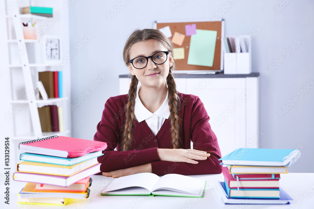 Teenage girl with pile of books sitting at desk in a classroom Teenage girl with pile of books sitting at desk in a classroom