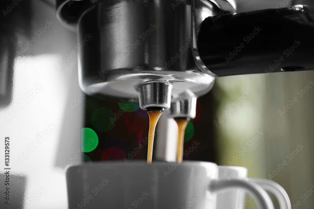 New coffee maker pouring fresh espresso into two cups, closeup New coffee maker pouring fresh espresso into two cups, closeup
