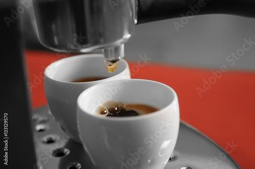 New coffee maker pouring fresh espresso into two cups, closeup