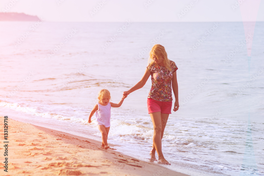 Mother and daughter walking along the beach