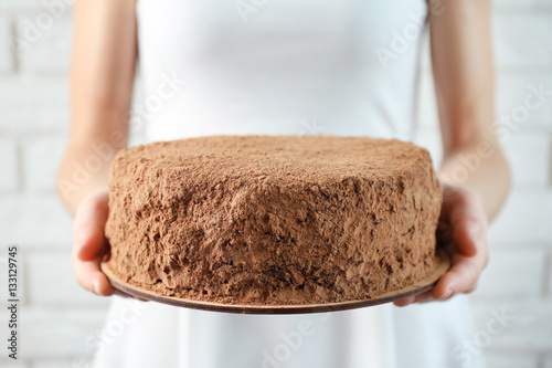 Woman holding chocolate cake on brick wall background