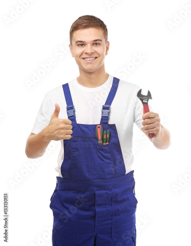 Young handsome plumber with wrench on white background