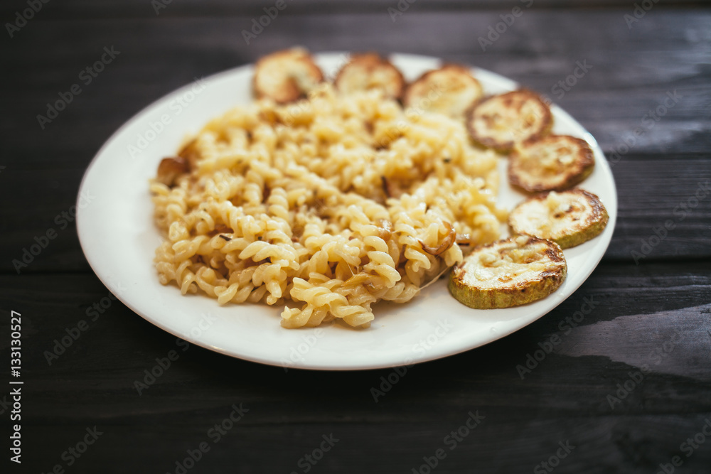 Pasta with fried zucchini on the plate on wooden background. Pasta with fried zucchini on the plate on wooden background.