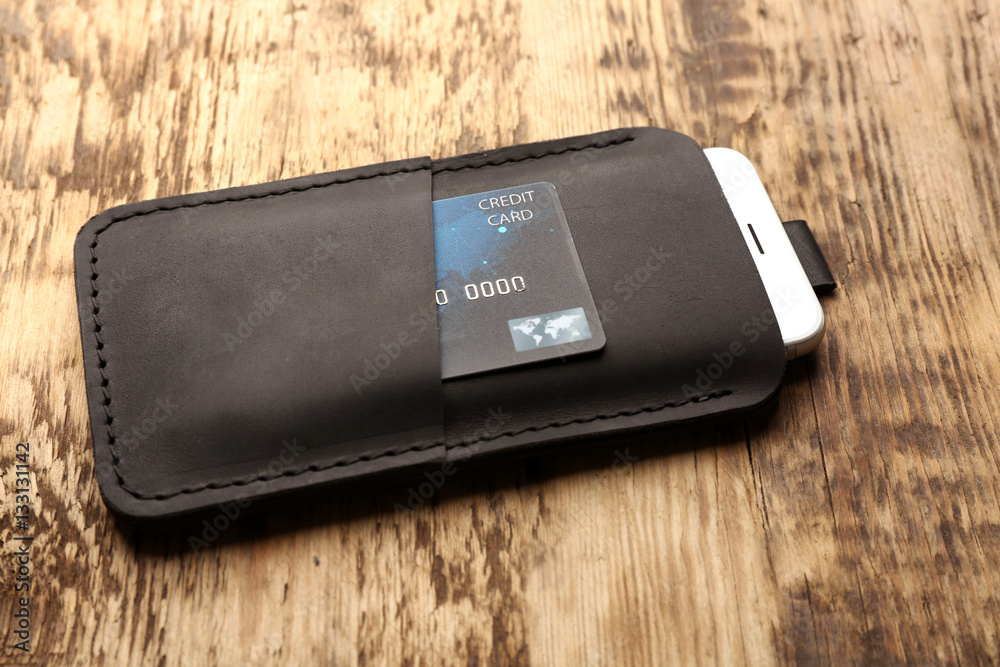 Leather case with mobile phone and credit card on wooden background Leather case with mobile phone and credit card on wooden background